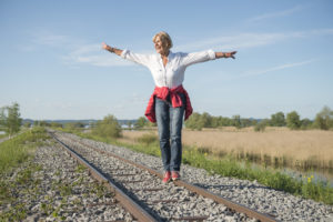 smiling senior lady having fun balancing on rails